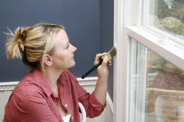 Woman painting a window frame with a small brush