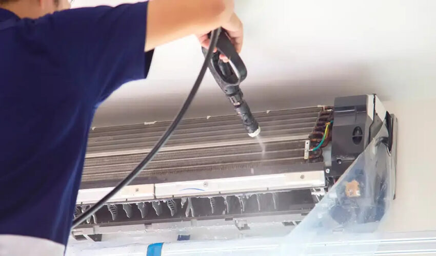 AC repairing service in Dubai with technician cleaning indoor AC unit coils