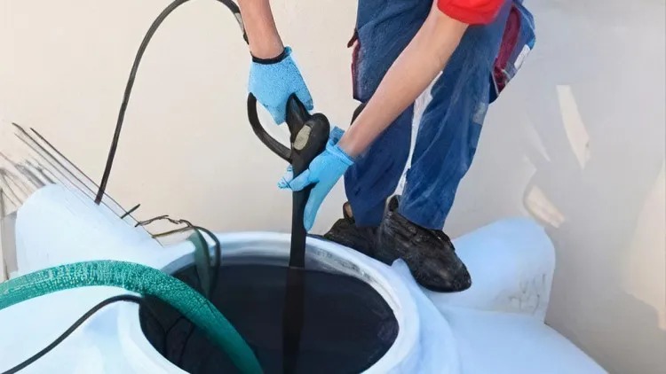 Water Tank Cleaners using professional vacuum equipment to clean and remove sludge from a residential water tank