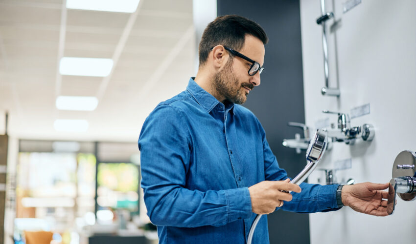 Plumbing Company in Dubai installing a modern commercial shower fixture and inspecting water connection system in a business facility.