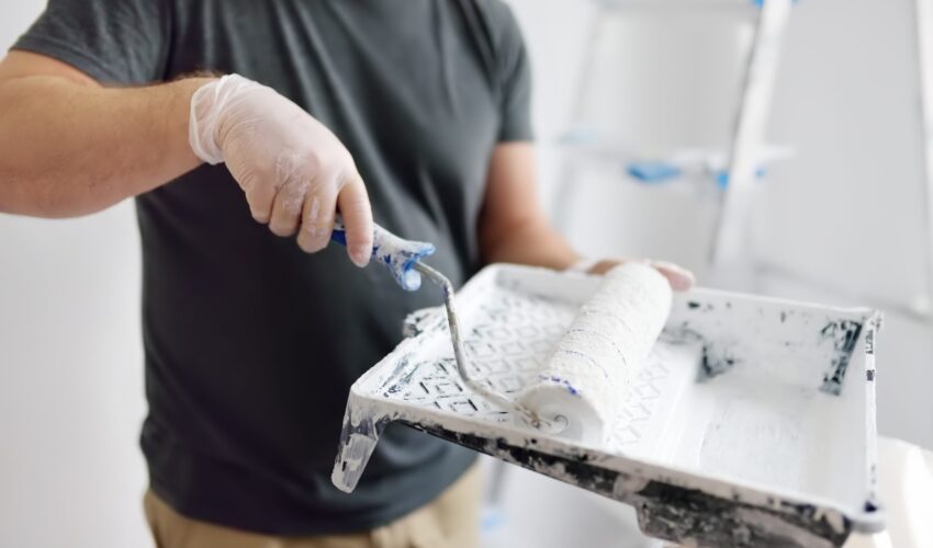 Dubai painter rolling white paint onto a wall using a paint tray during an interior apartment renovation.