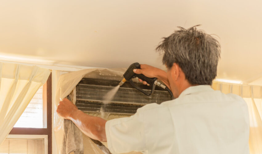 Technician performing professional AC vents cleaning with high-pressure equipment inside a Dubai home