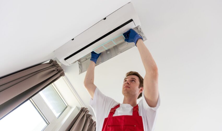 AC duct cleaning service technician inspecting and cleaning air conditioning unit