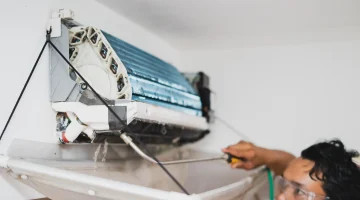 Technician servicing a split air conditioning unit on the wall.